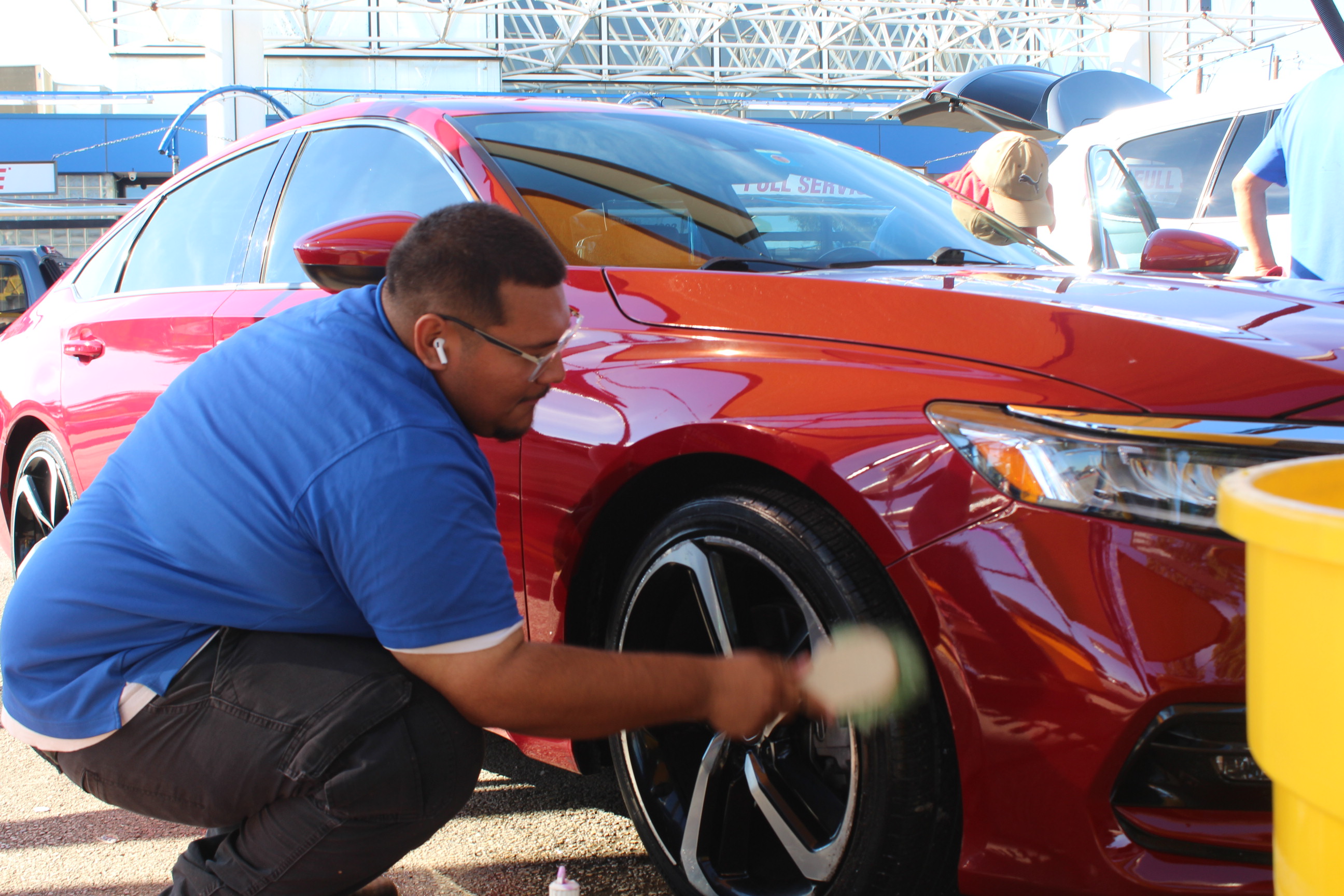 Auto Bath team member cleaning wheels on red Honda at Arlington location